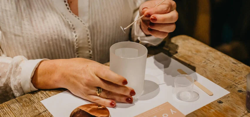 Person holding a small object over a white cup on a wooden table.